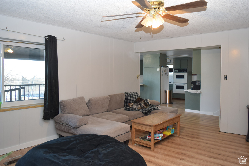 Living room with light wood-type flooring, ceiling fan, visible vents, and a textured ceiling