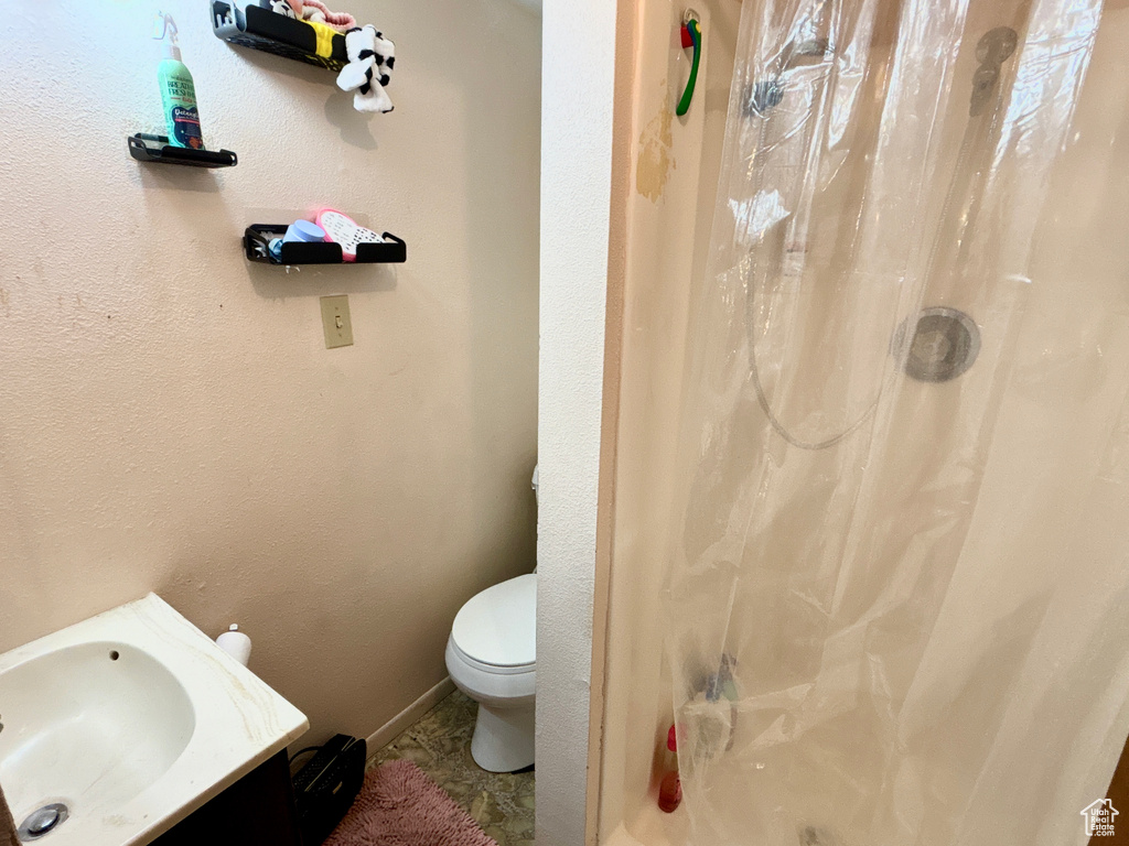 Full bath featuring toilet, baseboards, a sink, and a textured wall