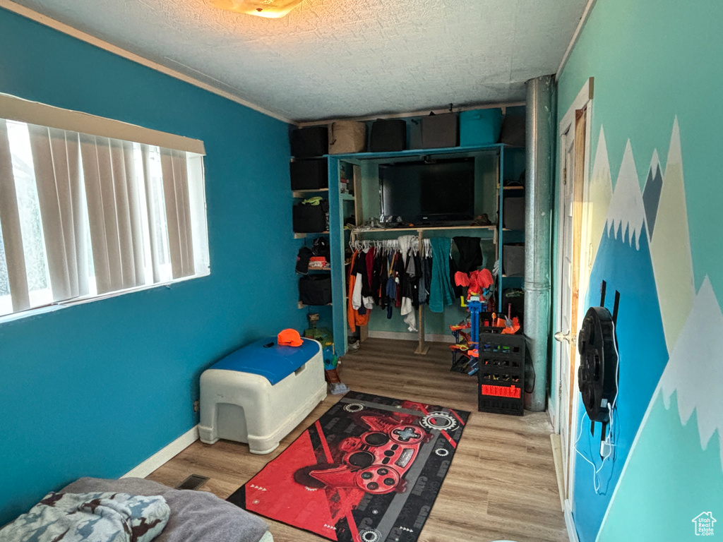 Bedroom featuring a closet, a textured ceiling, baseboards, and wood finished floors