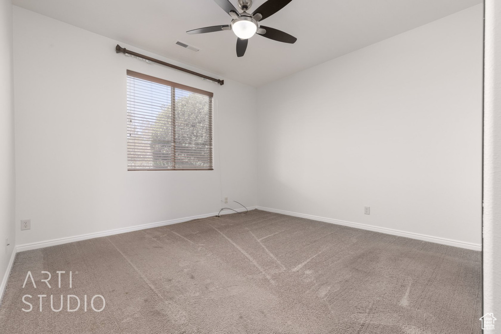 Carpeted spare room with a ceiling fan and baseboards