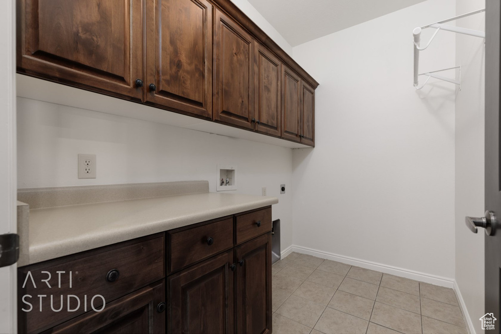 Washroom with cabinet space, washer hookup, baseboards, light tile patterned floors, and electric dryer hookup
