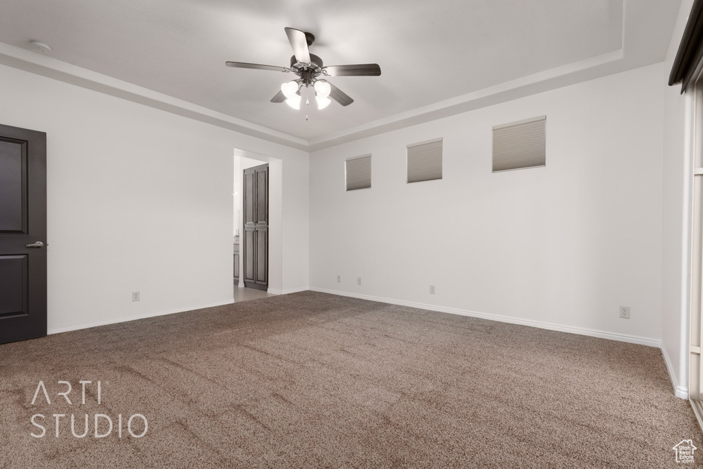 Carpeted empty room with ceiling fan, baseboards, a tray ceiling, and a smoke detector
