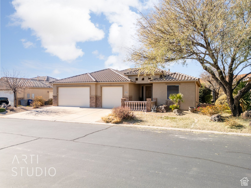 Mediterranean / spanish-style house featuring a garage, concrete driveway, stucco siding, and a tile roof