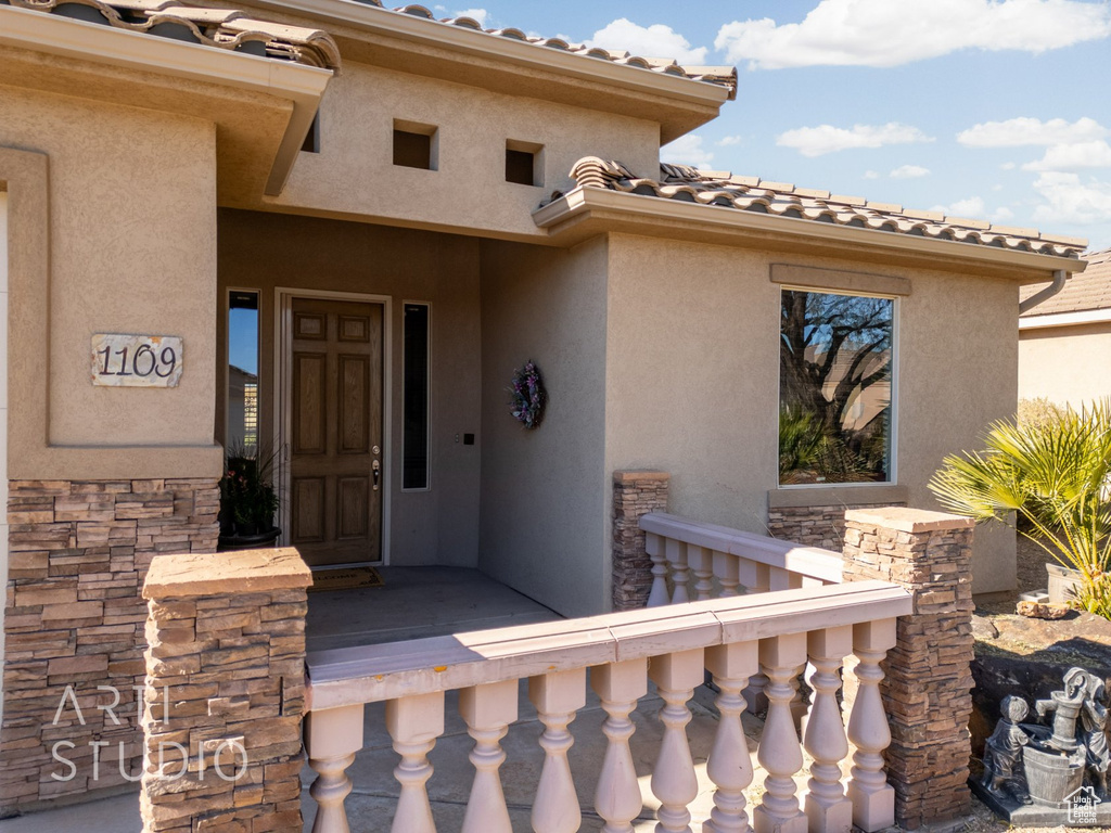 Property entrance with stucco siding, stone siding, and a tiled roof
