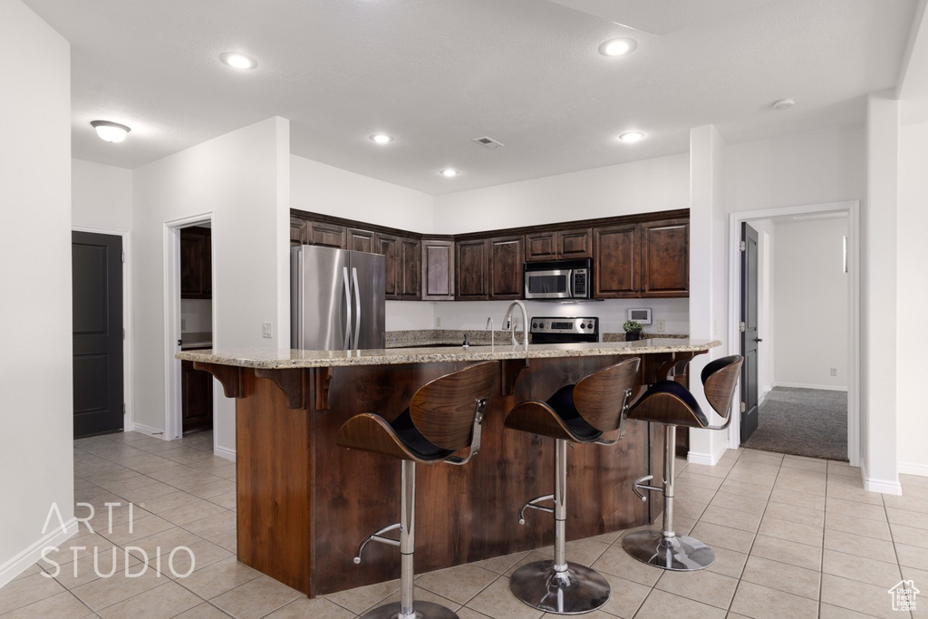 Kitchen with appliances with stainless steel finishes, baseboards, light tile patterned flooring, dark brown cabinets, and recessed lighting