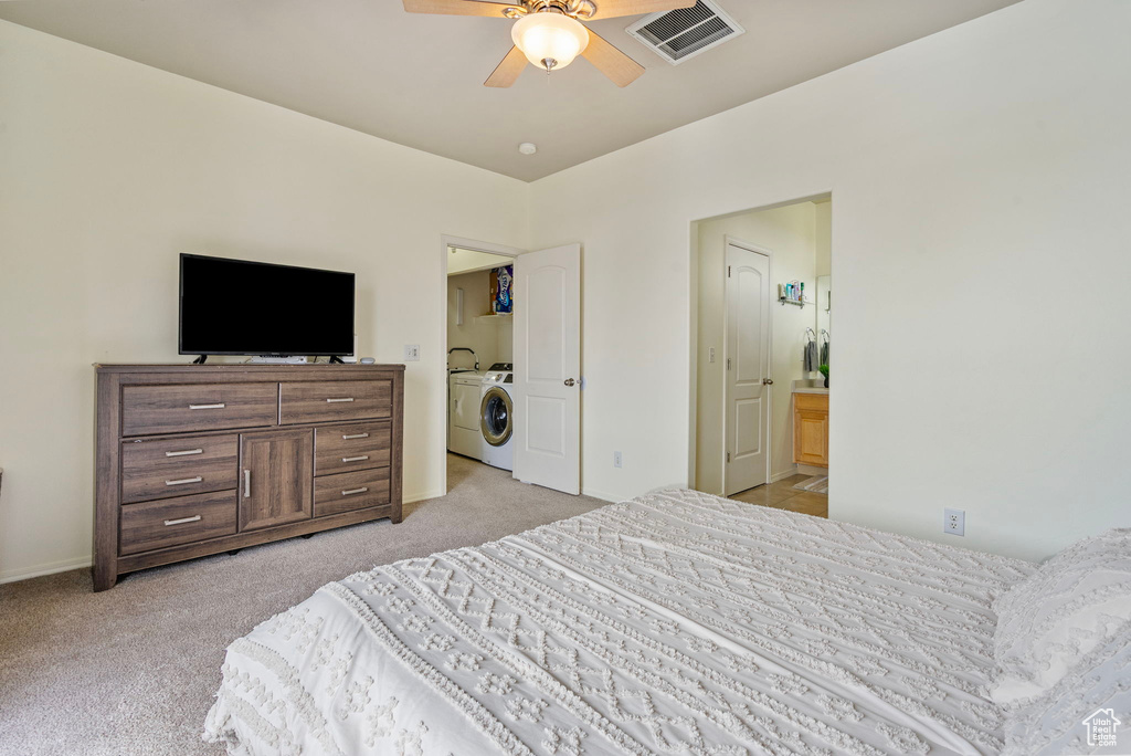 Bedroom with washer and clothes dryer, connected bathroom, visible vents, and light colored carpet