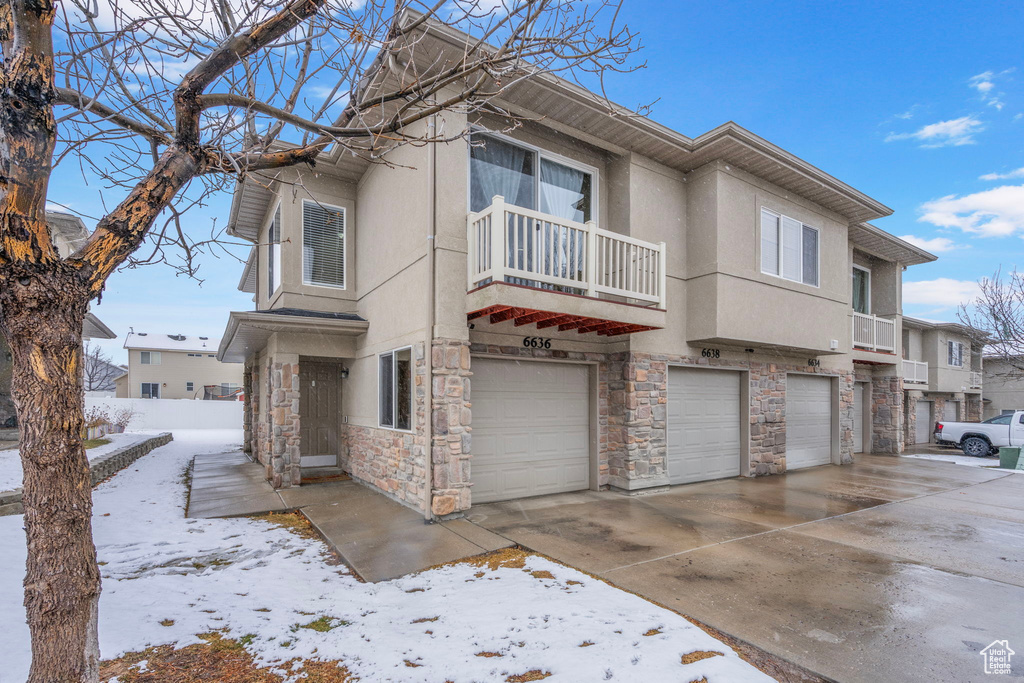 Multi unit property with driveway, an attached garage, a balcony, and stucco siding