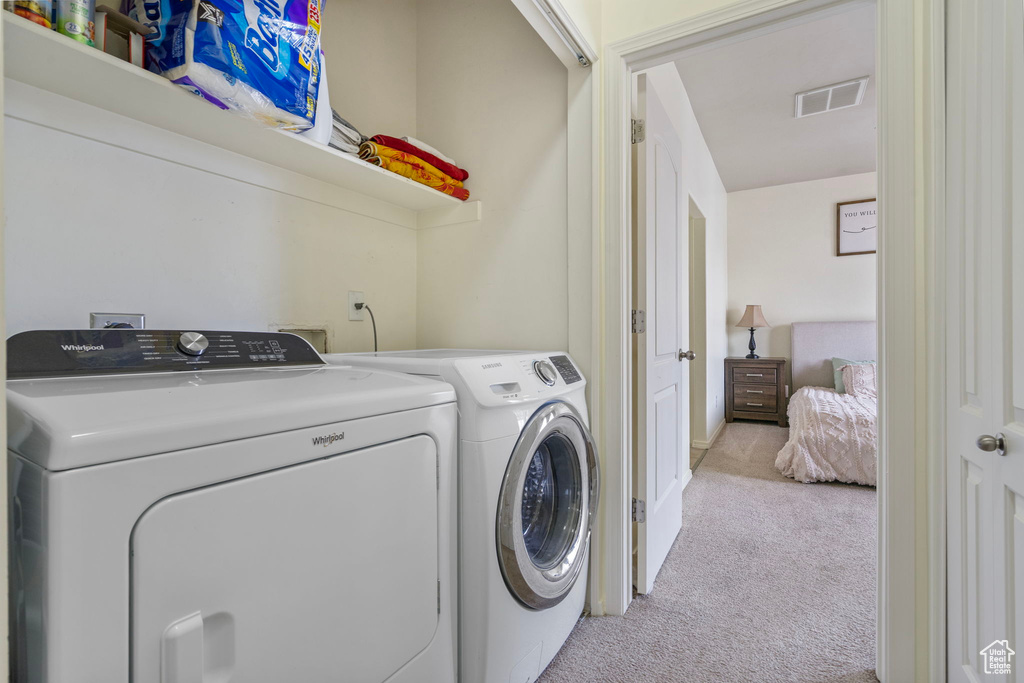 Laundry area featuring laundry area, separate washer and dryer, visible vents, and light colored carpet