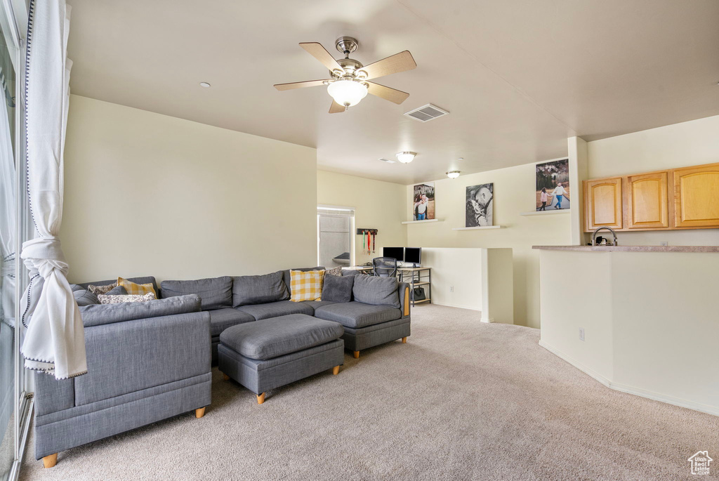 Living room featuring visible vents, ceiling fan, and light carpet