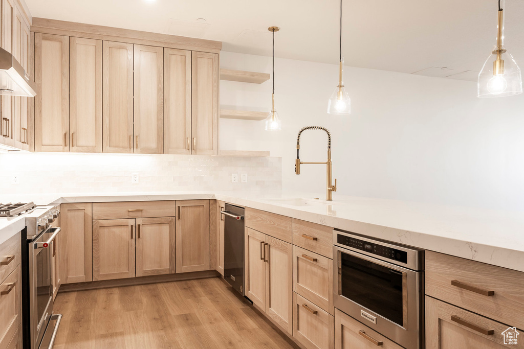 Kitchen featuring stainless steel appliances, open shelves, light brown cabinets, and light wood-style floors