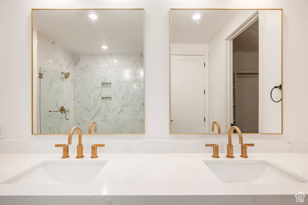 Bathroom with double vanity, a sink, and a marble finish shower