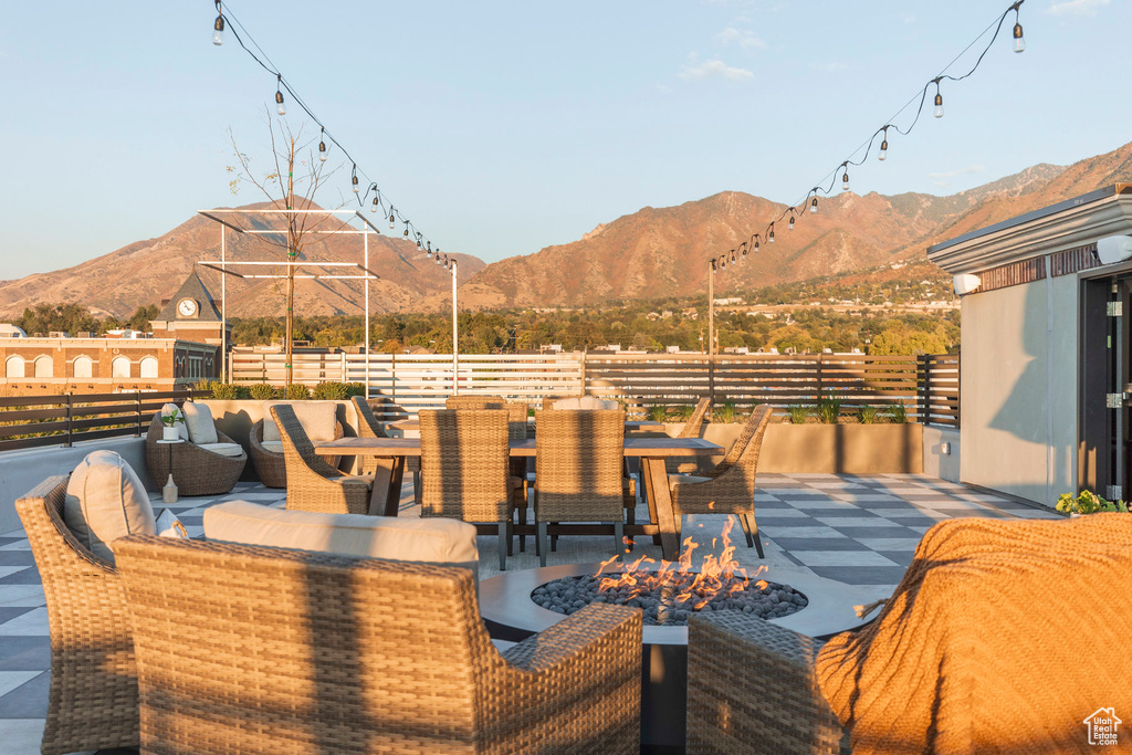 View of patio featuring an outdoor living space with a fire pit, fence, a mountain view, and outdoor dining space