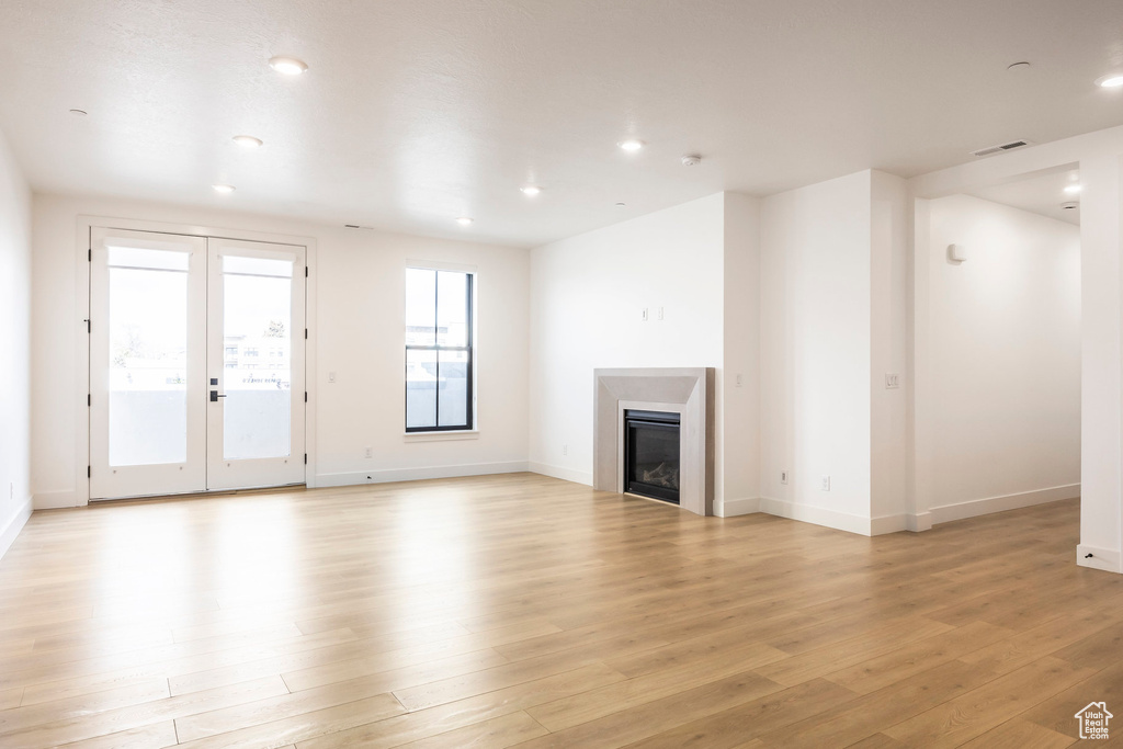 Unfurnished living room with light wood finished floors, a glass covered fireplace, visible vents, and recessed lighting