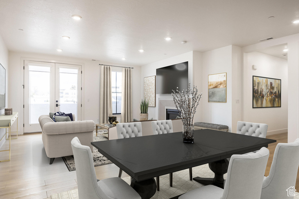Dining space with visible vents, baseboards, a glass covered fireplace, light wood-type flooring, and recessed lighting