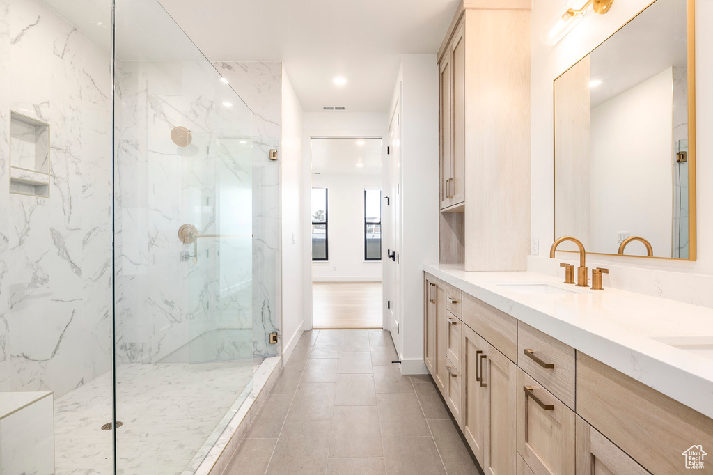 Bathroom with a marble finish shower, double vanity, visible vents, a sink, and baseboards