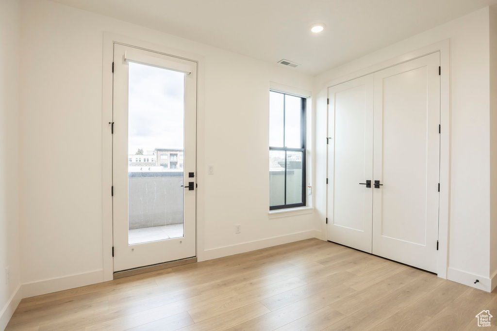 Doorway with light wood finished floors, baseboards, visible vents, and recessed lighting