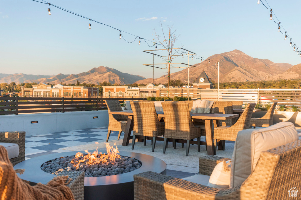 View of patio with outdoor dining space, a mountain view, a fire pit, and fence