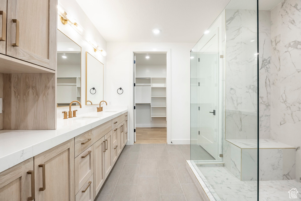 Bathroom with double vanity, a sink, a marble finish shower, and recessed lighting