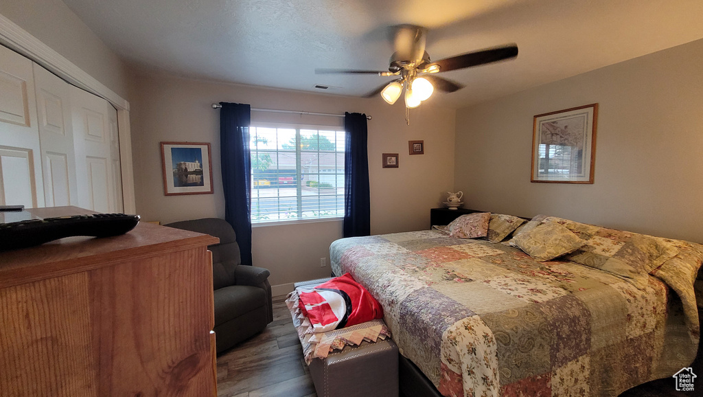 Bedroom featuring dark wood-type flooring, a closet, visible vents, and a ceiling fan