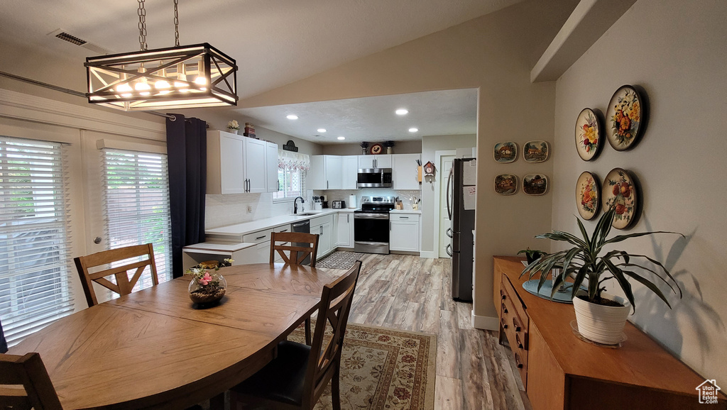 Dining space with vaulted ceiling, recessed lighting, visible vents, and light wood-style floors