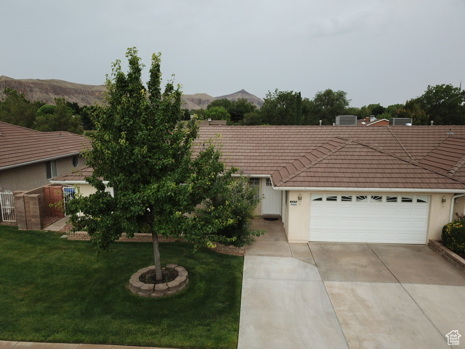 Ranch-style home with a tile roof, a mountain view, a front lawn, and concrete driveway