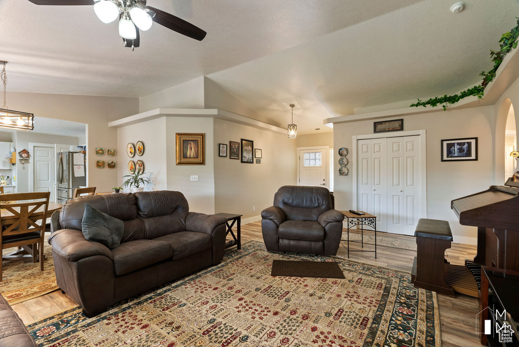 Living room featuring lofted ceiling, baseboards, a ceiling fan, and wood finished floors