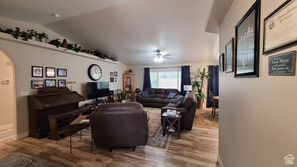 Living room with baseboards, arched walkways, lofted ceiling, ceiling fan, and wood finished floors