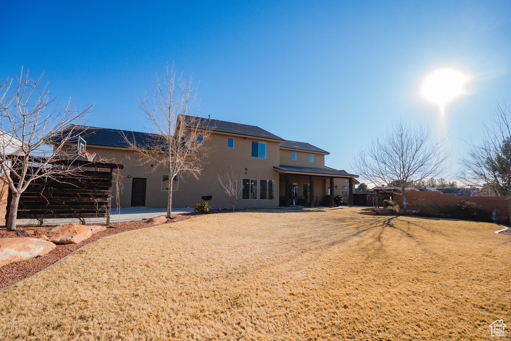 Rear view of house featuring a patio area, a yard, and stucco siding
