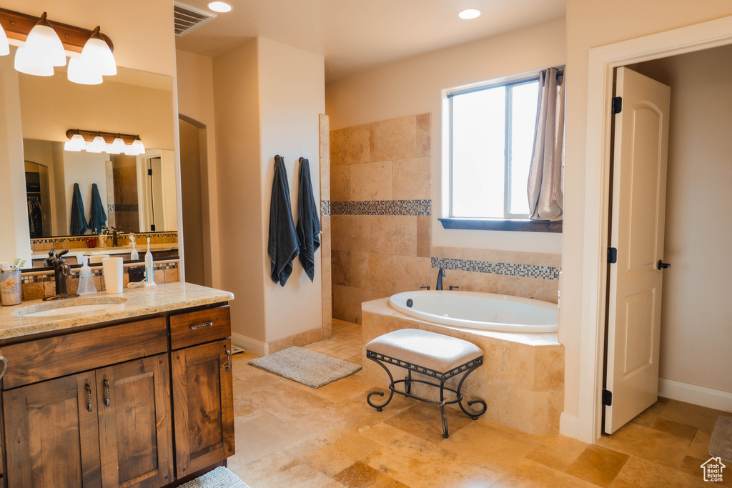 Full bathroom featuring a garden tub, recessed lighting, visible vents, vanity, and baseboards