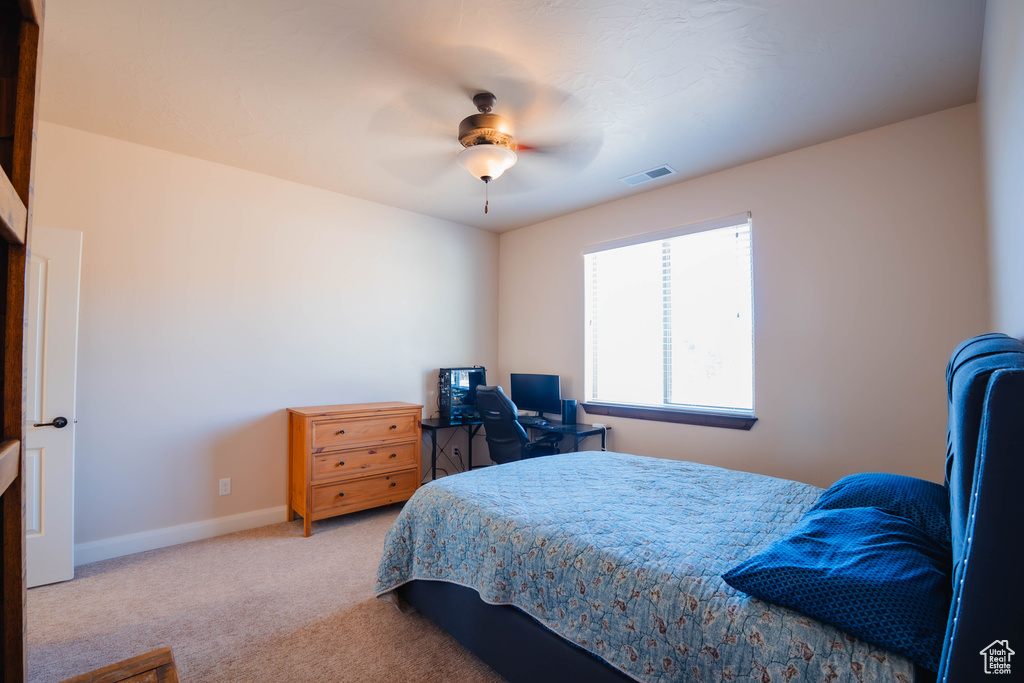 Bedroom featuring light carpet, ceiling fan, visible vents, and baseboards