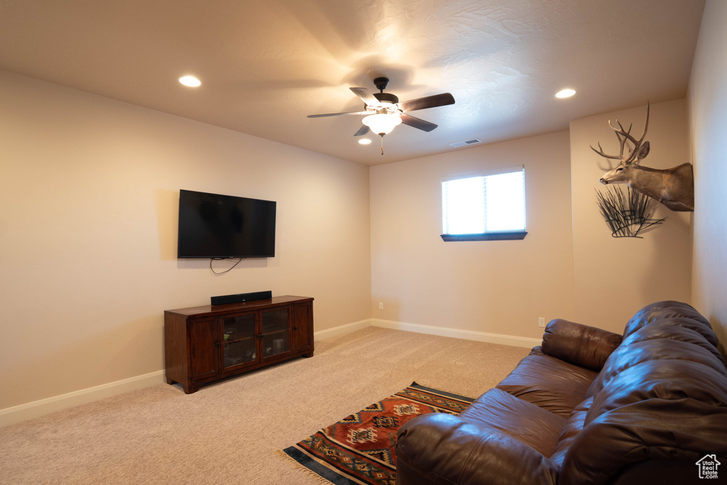 Living area with light carpet, ceiling fan, visible vents, and baseboards