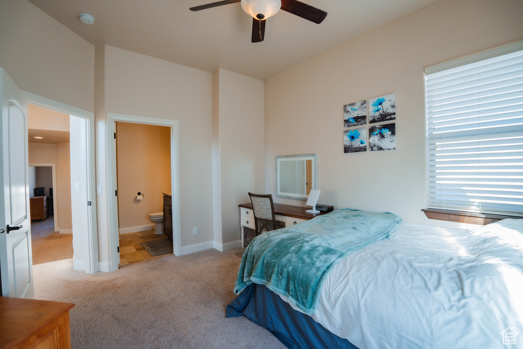 Bedroom featuring baseboards, ensuite bathroom, a ceiling fan, and light colored carpet