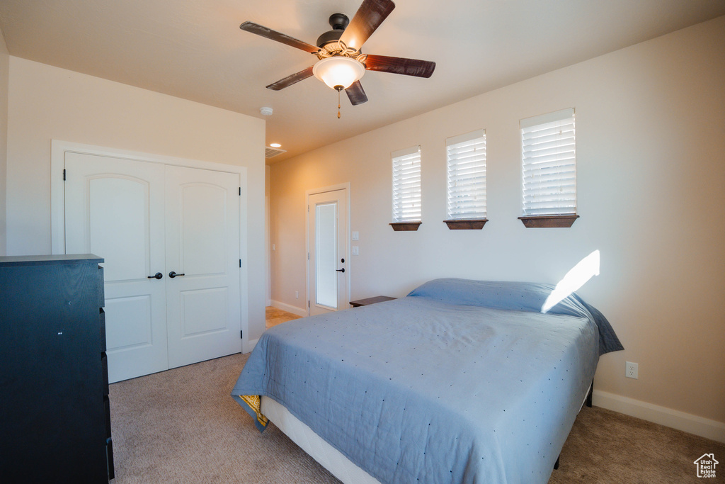 Bedroom featuring baseboards, a closet, a ceiling fan, and light colored carpet