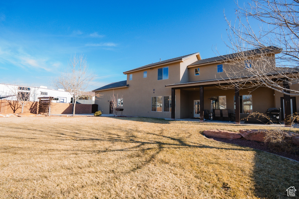Back of property featuring a yard, fence, and stucco siding