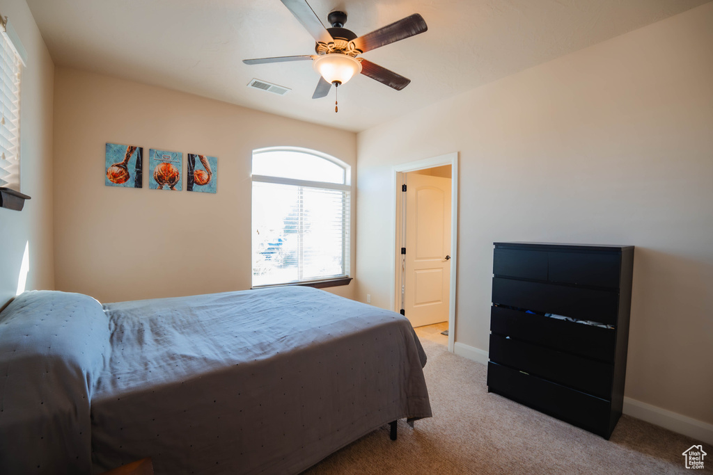 Bedroom with baseboards, visible vents, a ceiling fan, and light colored carpet