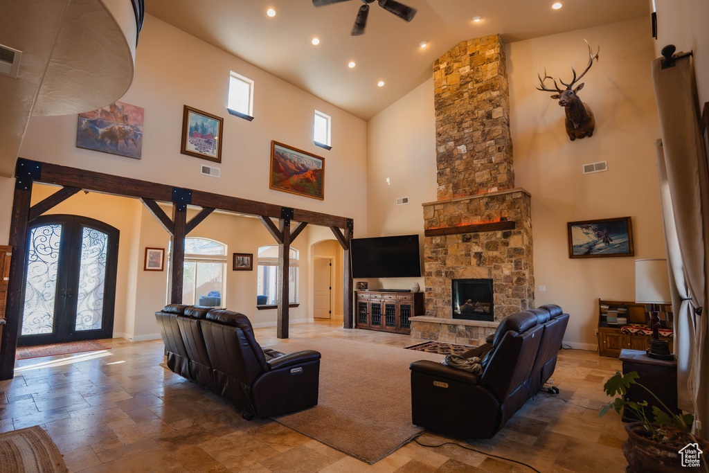 Living room with arched walkways, a stone fireplace, french doors, and visible vents