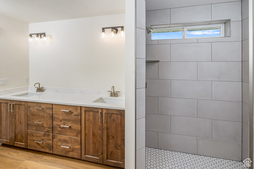 Bathroom with double vanity, a sink, and wood finished floors