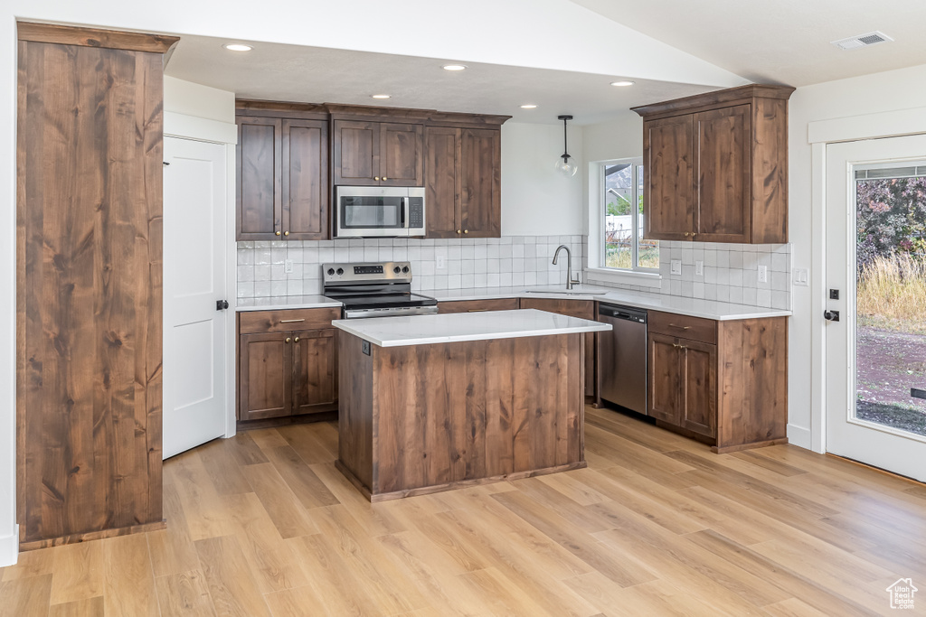 Kitchen featuring visible vents, a kitchen island, stainless steel appliances, light countertops, and a sink