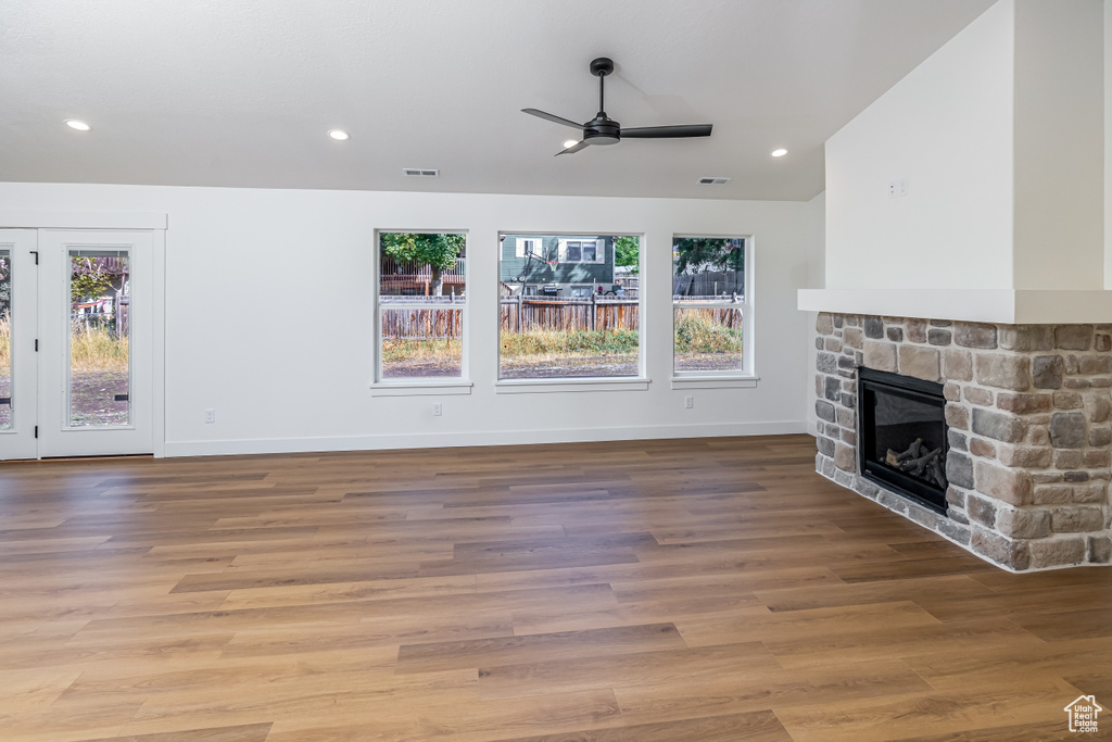 Unfurnished living room featuring a fireplace, wood finished floors, visible vents, and baseboards