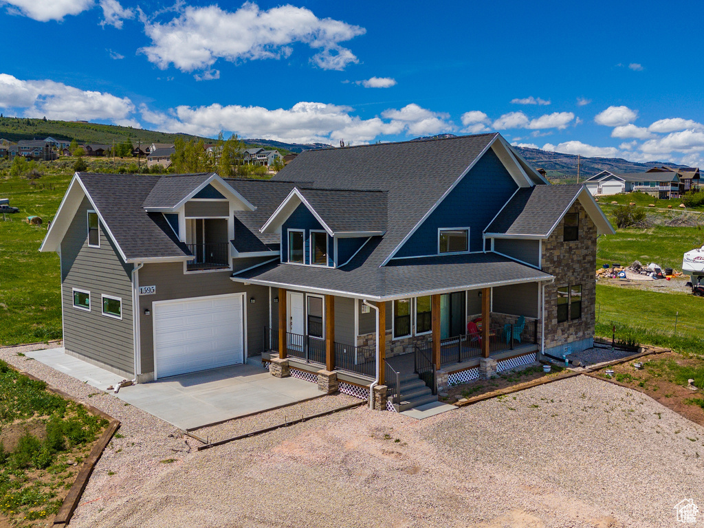 View of front facade featuring covered porch, driveway, a mountain view, and a garage