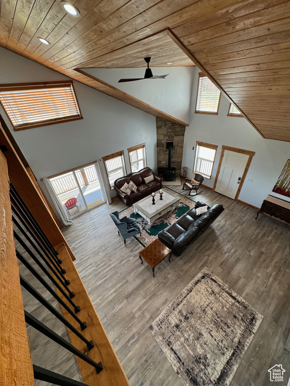 Unfurnished living room with wood ceiling, high vaulted ceiling, wood finished floors, and a wood stove