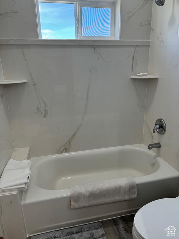 Full bath featuring wood finished floors, bathtub / shower combination, and toilet