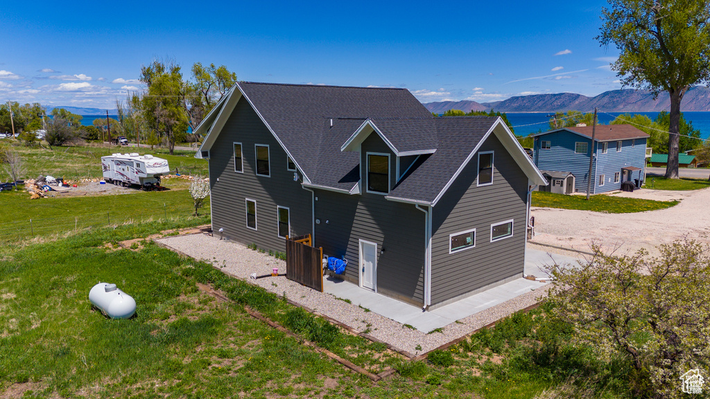 Exterior space featuring a shingled roof, a front lawn, and a mountain view