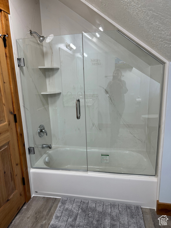 Bathroom featuring bath / shower combo with glass door and wood finished floors