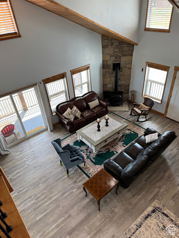 Living area with high vaulted ceiling, a wood stove, and a healthy amount of sunlight