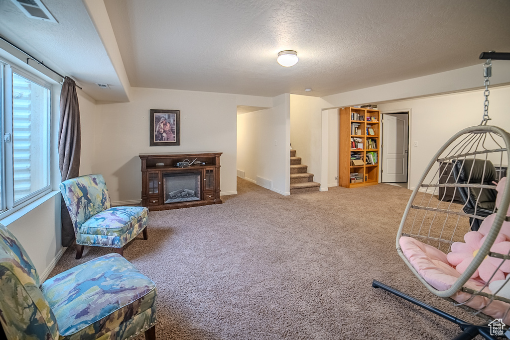 Living area featuring stairway, a textured ceiling, carpet flooring, a fireplace, and baseboards