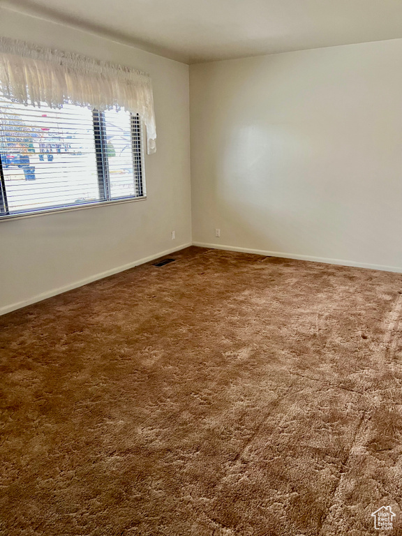Carpeted empty room with visible vents and baseboards