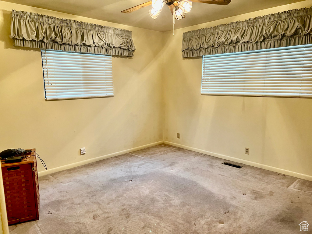 Carpeted spare room with ceiling fan, visible vents, and baseboards