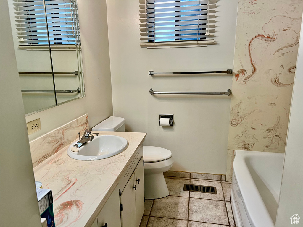 Bathroom with toilet, vanity, visible vents, a wealth of natural light, and a tub