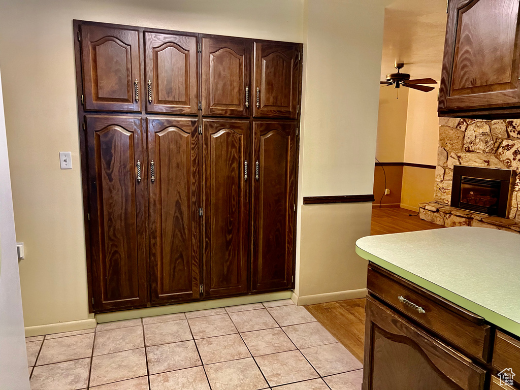 Kitchen featuring light countertops, a stone fireplace, and dark brown cabinets